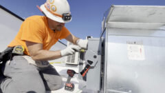 man in hard hat and orange shirt posing to do electrical work